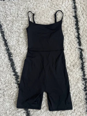 Svart byxdress med smala axelband - Säljer en svart byxdress med smala justerbara axelband. Den har en enkel, tight passform och är tillverkad i ett stretchigt material som formar sig efter kroppen. Storlek XS från Bik Bok 🖤