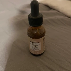 Skin Caffeine Face Serum med pipett - Ansiktsserum med koffein från Skin i en brun glasflaska med svart pipettlock. Perfekt för dig som vill boosta huden med extra energi och lyster. Flaskan rymmer 25 ml och har en enkel, stilren etikett.
