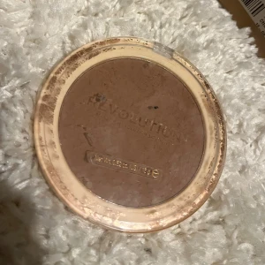 Revolution matt bronzer i puderform - Bronzer från Revolution i en varm, matt brun nyans. Kommer i en rund plastförpackning med transparent lock. Perfekt för att skapa solkysst look och definiera ansiktet. Pudret är pressat och lätt att applicera med borste.