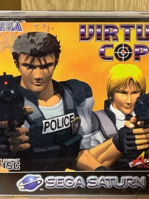 Virtua Cop till Sega Saturn - Virtua Cop är ett klassiskt actionspel till Sega Saturn där du spelar som polis och skjuter skurkar. Spelet levereras på CD och har en ikonisk tecknad omslagsdesign med poliser och vapen. Perfekt för dig som gillar retrospel och arkadskjutare.