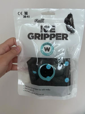Helt nya Kvill Ice Gripper halkskydd M - Säljer ett par svarta halkskydd från Kvill, modell Ice Gripper, i storlek M (38-41). De har blå dubbar och är tillverkade i slitstark TPE för bra grepp på isiga underlag. Perfekta att dra över skorna för extra säkerhet när det är halt ute.