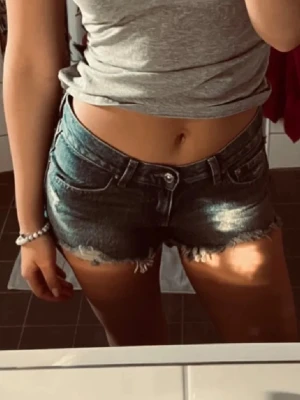 Lågmidjade jeansshorts  - Snygga blå jeansshorts från Gina Tricot med fransad kant och slitna detaljer. Klassisk femficksmodell med låg midja och knappgylf. Perfekta för varma dagar och en avslappnad stil. 🩷