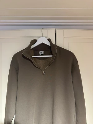 Brun halvzip tröja från ZARA - Säljer en brun långärmad tröja från ZARA. Perfekt för en avslappnad och stilren outfit. Endast använd ett fåtal gånger.