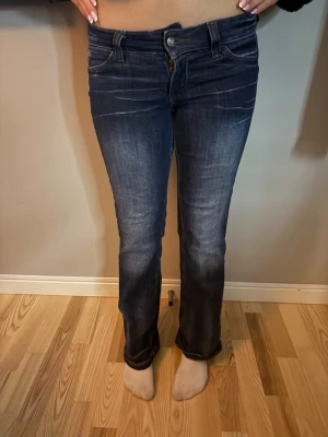 Mörkblå bootcut jeans Cheap Monday - Säljer ett par mörkblå bootcut jeans från Cheap Monday med snygga slitningar och klassisk femficksmodell. Jeansen har låg midja och är tillverkade i stretchigt denimtyg för skön passform. Perfekta till sneakers eller boots. Obs! Se defekt på baksidan. 