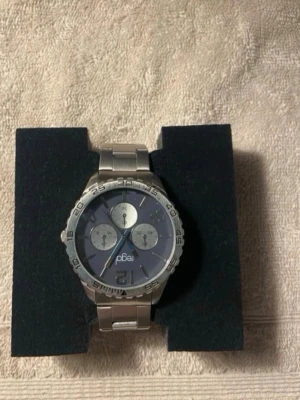 Regal silverfärgad kronografklocka - Stilren klocka från Regal med silverfärgat metallarmband och mörkblå urtavla. Klockan har tre mindre urtavlor och tydliga siffror på boetten. Perfekt accessoar för dig som gillar en klassisk men sportig look.