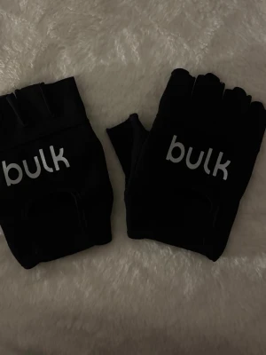 Svarta träningshandskar från Bulk - Säljer ett par svarta träningshandskar från Bulk med öppen fingertopp och insida i skinn. Helt nya.