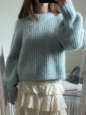 Ljusblå stickad tröja med ballongärm - Supermysig ljusblå stickad tröja med bred ribbstickning och ballongärmar. Tröjan har en avslappnad passform och rund halsringning. Perfekt för lager på lager och ger en soft vibe till din outfit. I mohair