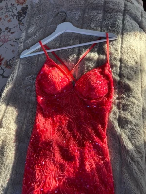 Korall paljettklänning med slits - Säljer en korall, figurnära klänning med tunna axelband och djup urringning. Klänningen är täckt av paljetter och har ett snyggt mönster samt en hög slits framtill. Perfekt för dig som vill sticka ut med en glittrig look. Endast använd 1 gång där släpet är smutsigt men inget som märks när man har på den💕Storlek 2 (32) men passar mig som vanligtvis har Xs/s. Pris kan diskuteras vid snabb affär ☺️