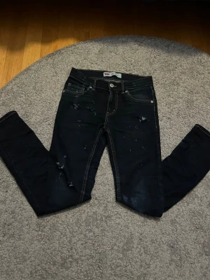Svarta skinny jeans från Levi's - Säljer ett par svarta skinny jeans från Levi's med slitningar och distressed detaljer. Jeansen har fem fickor, silverfärgade nitar och klassisk Levi's-lapp bak. Snygg passform och stretchigt material som sitter tajt hela vägen ner.