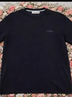 Svart t-shirt från Lacoste - En stilren svart t-shirt från Lacoste med diskret logga på bröstet. Klassisk rund halsringning och korta ärmar. Perfekt basplagg i garderoben och lätt att matcha med andra plagg.