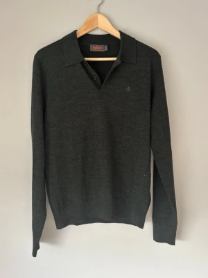 Mörkgrön stickad tröja från Morris - Snygg mörkgrön stickad tröja från Morris med krage och knappar vid halsen. Tröjan har lång ärm och diskret logga broderad på bröstet. Tillverkad i mjukt material som passar perfekt till en stilren look.