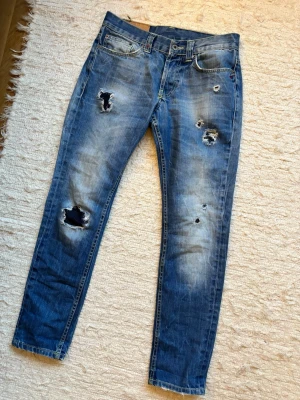 DONDUP JEANS MED SLITNINGAR - Ett par DonDup jeans med flera slitningar vilket är väldigt eftertraktat! Storlek 30, modellens namn är okänt men passar slim. Hör av dig vid frågor!