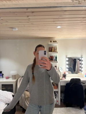 Grå basic stickad tröja - Enkel och stilren grå stickad tröja med rund halsringning och långa ärmar. Tröjan har en rak passform och ribbade muddar vid ärmslut och nederkant. Perfekt att matcha med jeans eller kjol för en avslappnad look.