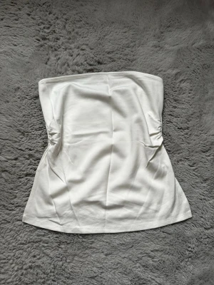 Vit bandeau tubtopp - Säljer en enkel och stilren vit bandeau tubtopp. Storlek L men sitter som en M