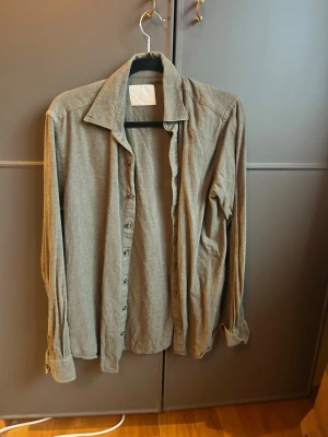 Mörkgrön Oscar Jacobsson skjorta i bomull - En stilren grön skjorta med klassisk krage och knappar framtill. Skjortan är långärmad och har en avslappnad passform. Tillverkad i mjuk bomull som känns skön mot huden. Perfekt att bära öppen över en t-shirt eller knäppt för en mer uppklädd look.