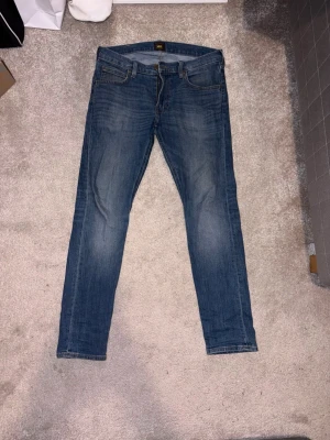 Lee Luke 30 - Snygga blå slim fit jeans från Lee i stl 30W 30L. Perfekta för en avslappnad och trendig look. Hör av dig vid frågor och funderingar!
