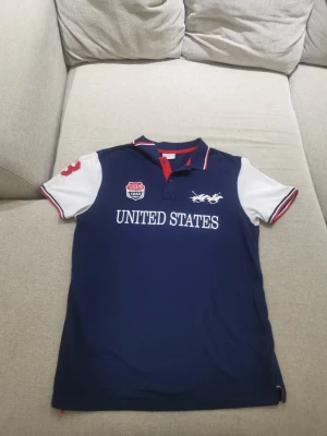 Blå pikétröja från U.S. Polo Assn. - Säljer en jätte snygg Polo Assn pikétröja som är i jättebra skick! Har använts vid 2 tillfällen. Det finns små svarta fläckar på ena sidan av ärmarna (sista bilden), men syns inte på långt avstånd.  Storlek L men passar till M, hör av dig vid frågor!