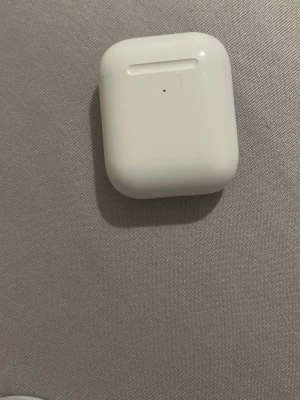 Vita trådlösa hörlurar Apple AirPods - Säljer ett par vita trådlösa hörlurar från Apple, modell AirPods, med laddningsetui i blank plast. Smidig och kompakt design som är enkel att ta med sig. Perfekt för musik, poddar och samtal när du är på språng. DE ÄR INTE RIKTIGA KÖP PÅ EGEN RISK