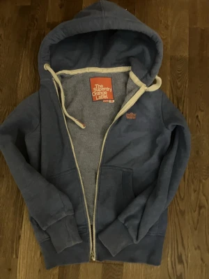Blå superdry zipp - Säljer en blå hoodie från superdry. Bra skick, nästan inga tecken på distress.Priset är inte ristat i sten. Kom gärna med frågor eller prisförslag.  Storlek : S 