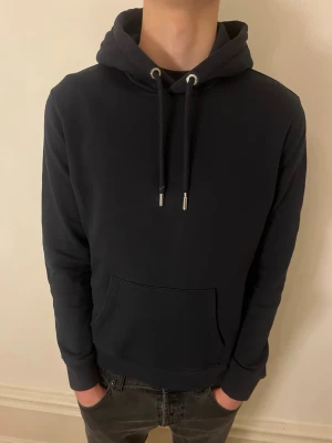 Mörkblå hoodie från John Henric - Säljer min oanvända hoodie från John Henric Jag på bilden är 184cm lång och väger 70kg. Tröjan är rätt så stor i storleken men passar framförallt dem under 182. Hör av dig vid frågor och funderingar!