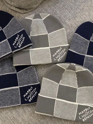 Louis Vuitton (En för 700 Kronor) - Snygga mössor med rutigt mönster i grått och marinblått från Louis Vuitton. Mössorna har broderad text på sidan och är stickade i mjukt material. Perfekt accessoar för att lyfta din streetwear-stil. En för 700 Kronor inte alla för 700 kronor!!