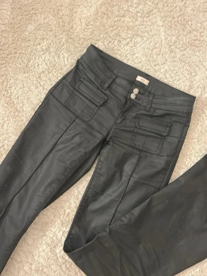 Svarta coated jeans från Nelly - Snygga svarta coated jeans från Nelly, med låg midja💕