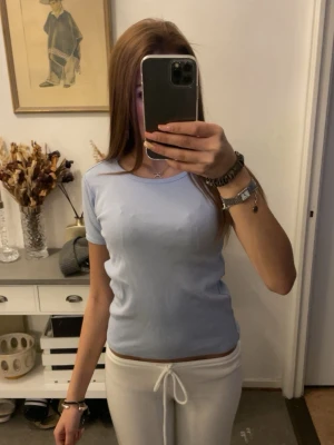 Ljusblå ribbad topp med kort ärm - Snygg ljusblå ribbad topp med rund halsringning och korta ärmar. Enkel och stilren design som passar perfekt till jeans eller kjol. Mjuk och stretchig för en bekväm passform.