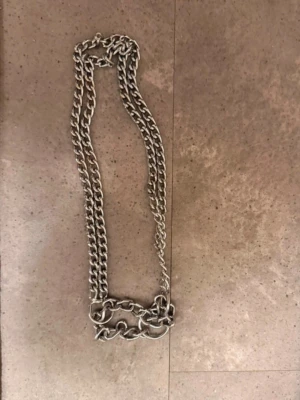 Tungt silverfärgat hundkedja - Säljer ett chunky halsband i silverfärgad metall med grova länkar. Kedjan har en cool och edgy vibe, perfekt för att lyfta vilken outfit som helst. Inget synligt märke på halsbandet. Passar dig som gillar statement-smycken.