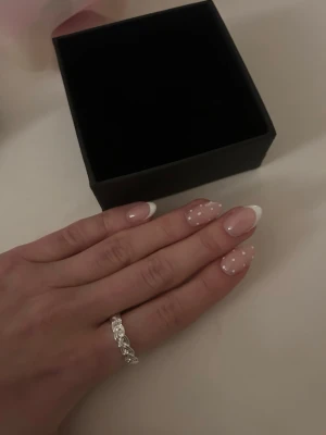 Flätad silverring i minimalistisk stil - Snygg ring i silverfärgat material med flätad design som ger en trendig och stilren look. Ringen har en tunn och elegant form som passar perfekt för dig som gillar minimalistiska smycken