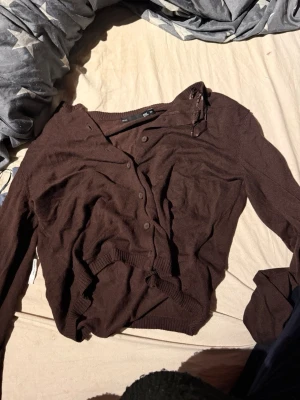 Brun kofta från H&M - Mysig brun kofta från lager157 med knappar framtill och ribbade muddar vid ärmslut och nederkant. Långärmad och i tunt, mjukt material som passar perfekt för lager på lager. Enkel och stilren design.