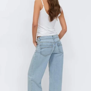 ultra low wide jeans från Gina Tricot - Säljer ett par ljusblå jeans från Gina Tricot. Vida jeans med låg midja. Jeansen är blåa och har vida ben med fullängd. De har komfortstrech, normal passform, dragkedjegylf, midjeband med bälteshällor, framfickor och bakfickor med sömdetaljer.