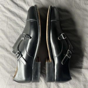 Finskor läder, randsydda, knappt använda - Har ett par svarta Meermin finskor gjorda av ”calf leather” med double monk-strap och randsydd/”goodyear welt” konstruktion, riktigt rejäla. Använda kanske 3-4 gånger men aningen för små för mig så legat oanvända sen dess. Första två bilderna är mina egna, de andra två från deras hemsida. Nypris +2000kr.