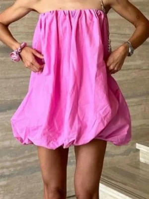 Rosa axelbandslös kortklänning - Supersöt rosa kortklänning med axelbandslös design och luftig ballongform. Perfekt för varma dagar och enkel att styla med accessoarer. Klänningen har en avslappnad passform och är tillverkad i ett lätt material. Andra bilden är lånad