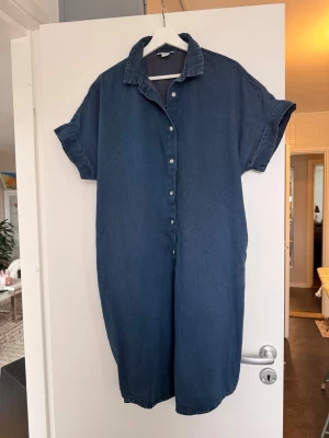 Blå jeansklänning med kort ärm - Jeansklänning i rymlig modell från Monki.Fickor på sidorna.
