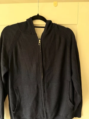 Mörkblå ziptröja med hög krage från loro piana - Mysig mörkblå ziptröja med hög ribbad krage och långa ärmar. Tröjan har dragkedja framtill och två fickor på sidorna. Perfekt för lager på lager och enkel att matcha med olika outfits.