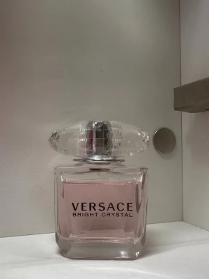 Versace Bright Crystal parfym 30ml - Versace Bright Crystal parfym i en elegant glasflaska med ljusrosa doftvätska. Flaskan har en exklusiv, kristalliknande kork och rymmer 30 ml. En ikonisk doft från Versace som ger en fräsch och feminin känsla. Lite använd.