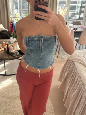 Blå denim tubtopp Zara - Trendig tubtopp i blå denim med råa sopade kanter och synligac sömmar.  Toppen är axelbandslöslös och har en croppad passform. Perfekt för dig som vill perfa en edgy och unik stil.