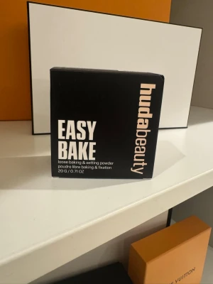 Huda Beauty Easy Bake Banana Bread - Loose baking & setting powder från Huda Beauty i nyansen Banana Bread. Kommer i en svart fyrkantig förpackning med tydlig märkning. Perfekt för att fixera basen och ge en matt finish. Innehåller 20 g puder. HELT NY