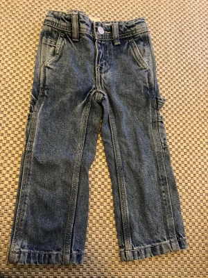 Blå cargobyxor i denim - Snygga blå cargobyxor i denim med flera fickor på sidorna och baktill. Byxorna har raka ben, bälteshällor och klassisk knappstängning. Perfekta för en avslappnad och cool stil.