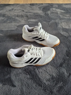 Vita Adidas sneakers med svarta ränder - Fräscha vita sneakers från Adidas med klassiska svarta ränder på sidorna och gummisula i ljusbrun färg.  Obetydligt använda,max 2-3 gånger kortare stunder