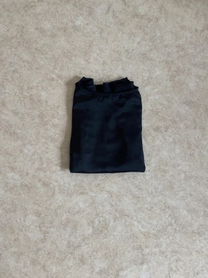 Svart satinblus med trekvartsärm - Stilren svart blus i glansigt satinmaterial med rund halsringning och trekvartsärmar. Perfekt för dig som diggar enkel men elegant look. Blusen har en rak passform och känns både mjuk och lätt på kroppen.