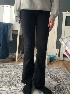 Svarta bootcut jeans - Säljer ett par svarta bootcut jeans med hög midja och utsvängda ben. Jeansen har klassisk femficksdesign och är i stretchigt material som sitter snyggt. Perfekta till sneakers eller boots för en trendig look.