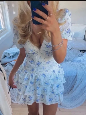 Vit blommig volangklänning - Supersöt kort klänning i vitt med blått blommönster och volanger, den är i storlek s och är väldigt i bra skick! Sälj inte längre i butik!💕