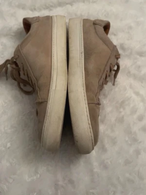 Beige mockasneakers med vita sulor - Snygga beige sneakers i mocka  med vita, tjocka gummisulor. Klassisk låg modell med snörning. Perfekta för dig som gillar stilrena och neutrala sopor till vard Hgarderob.
