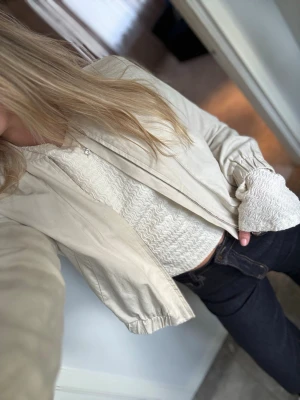 Ljusbeige tunn bomberjacka  - Snygg beige (lättglansig) bomber jacka med resår-muddar vid ärmslut och midja. Jackan har en enkel design från STOCKH LM. Jag är egentligen en medium och den sitter helt okej på mig då den är XS.