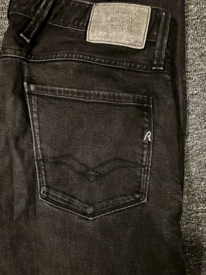 Replay anbass - Säljer ett par svarta jeans från Replay med klassisk femficksmodell. Jeansen har snygga detaljer på bakfickan och Replay-logga på etiketten bak. Materialet är denim med en skön stretch och passformen är normal. Perfekta till en avslappnad stil.