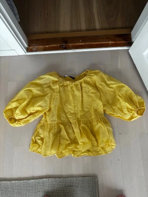 Gul volangblus från Zara - Snygg gul blus från Zara med volanger och puffiga långärmar. Tillverkad i ett lätt, strukturerat tyg som ger en luftig känsla. Perfekt för dig som vill ha en färgglad och trendig look med extra volym i ärmarna.💛