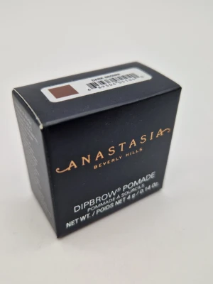 Anastasia Dipbrow Pomade Dark Brown - Anastasias Dipbrow Pomade i färgen Dark Brown ger fylliga och definierade bryn. Krämig formula som är lätt att applicera och bygga upp för ett naturligt eller markerat resultat. Kommer i en liten svart förpackning med guldtext.