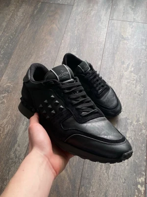 Valentino Rockrunners Skor - Säljer ett par riktigt snygga Valentino Rockrunners i färgen svart. Dessa är väldigt välkända och snygga. Skicket är 7/10 då lite nitar är av, men de är snyggt. Storleken är 43. Priset kommer ligga på 1199kr men kan sänkas.