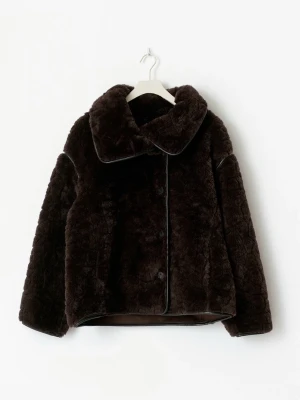 Mörkbrun teddyjacka - Säljer en fluffig mörkbrun teddyjacka med bred krage och knappstängning framtill. Jackan har en boxy passform och långa ärmar, perfekt för dig som vill ha en mysig och trendig look. Materialet är mjukt och ger en lyxig känsla.